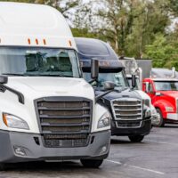 camiones grandes de semirremolque, tractores con remolques cargados, están estacionados en fila